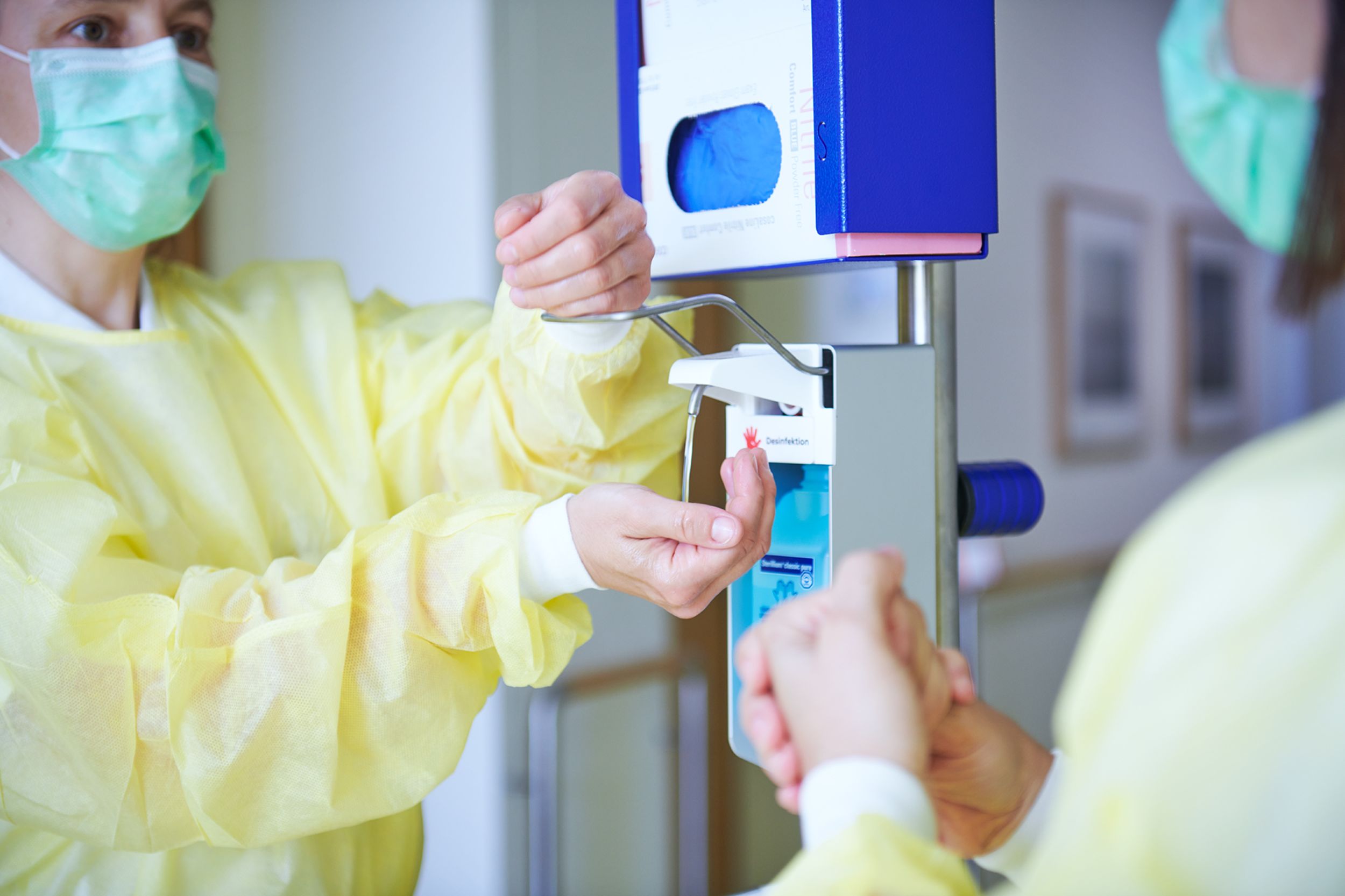 Two hospital hygiene staff disinfecting hands