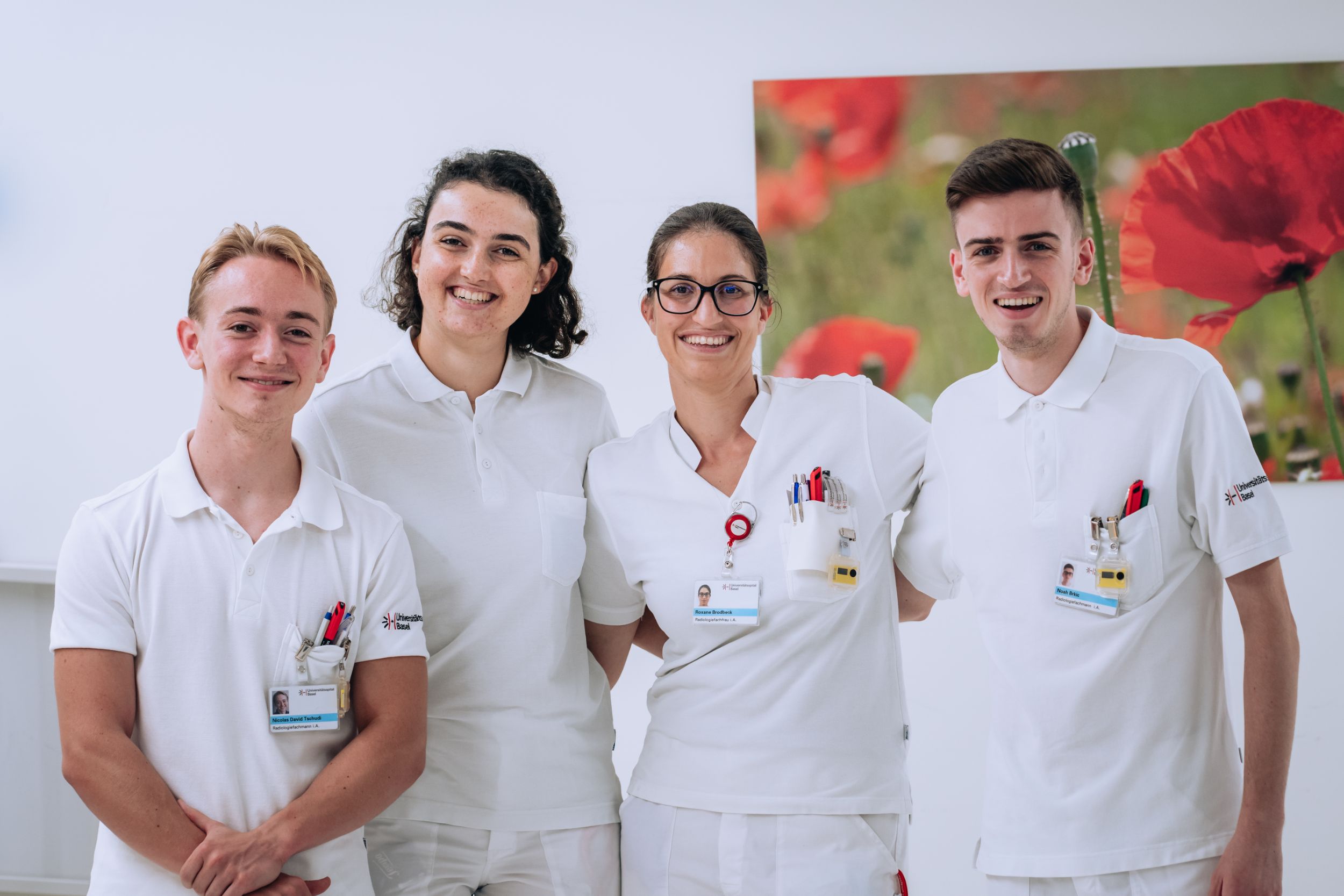 Vier Radiologiefachpersonen in Ausbildung stehen vor einem Bild nebeneinander