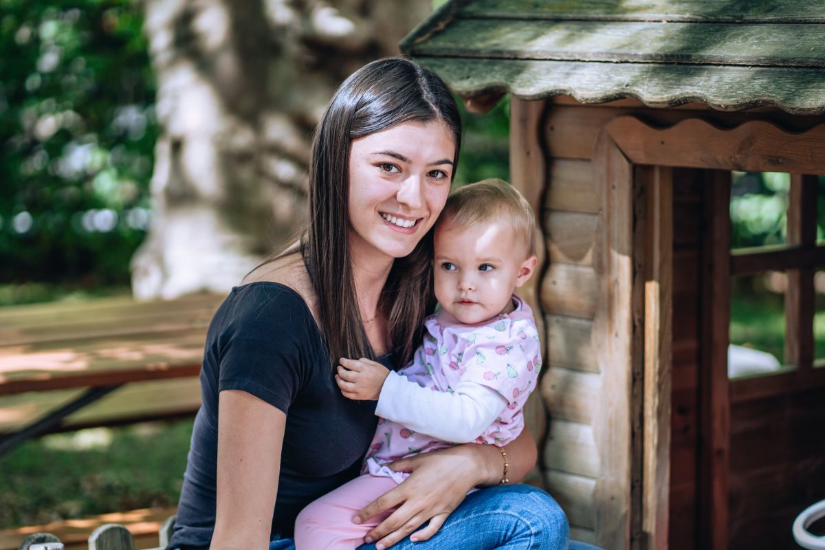 Fachfrau Betreuung sitzt mit einem Kleinkind auf einer Bank