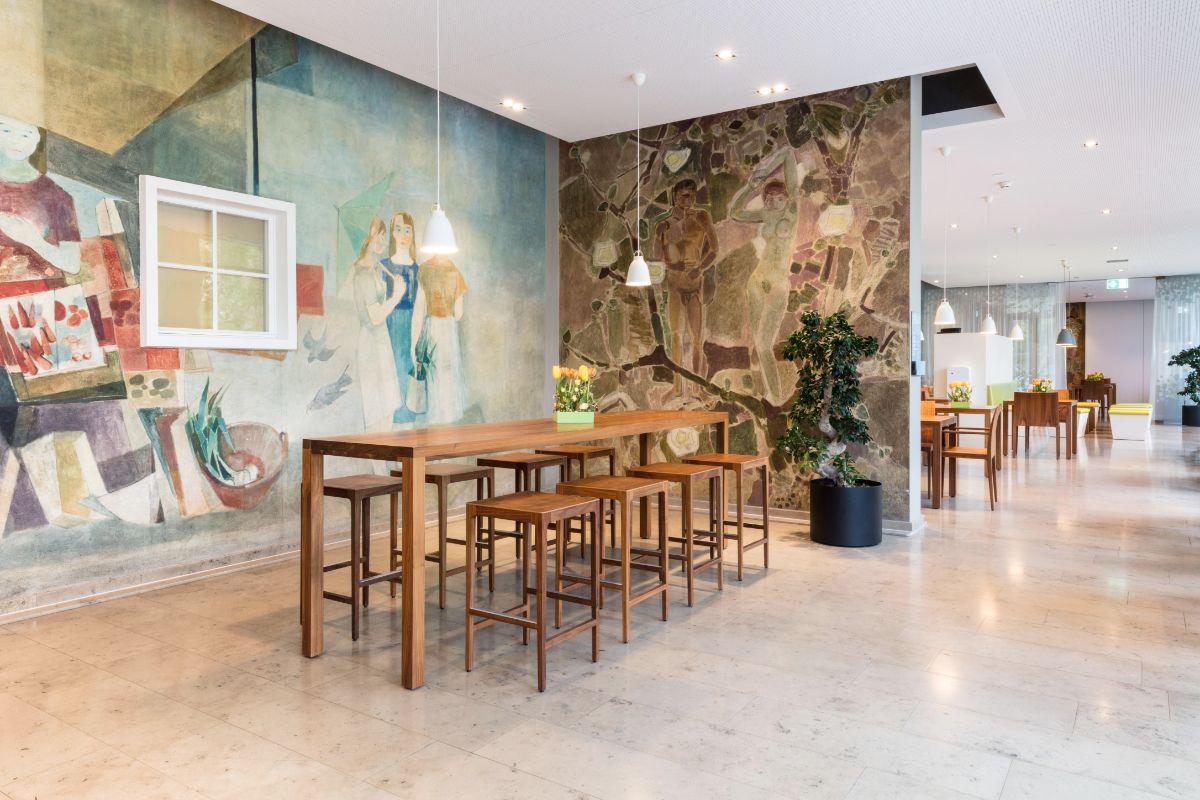 Blick in das Restaurant Giardino, heller Raum mit Steinfassade und einem Hochstich mit Stühlen in der Front