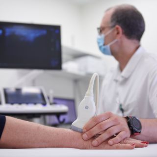 Arzt führt eine Ultraschall-Untersuchung an Hand von Patientin durch