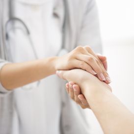 Ärztin hält Hand von Patientin