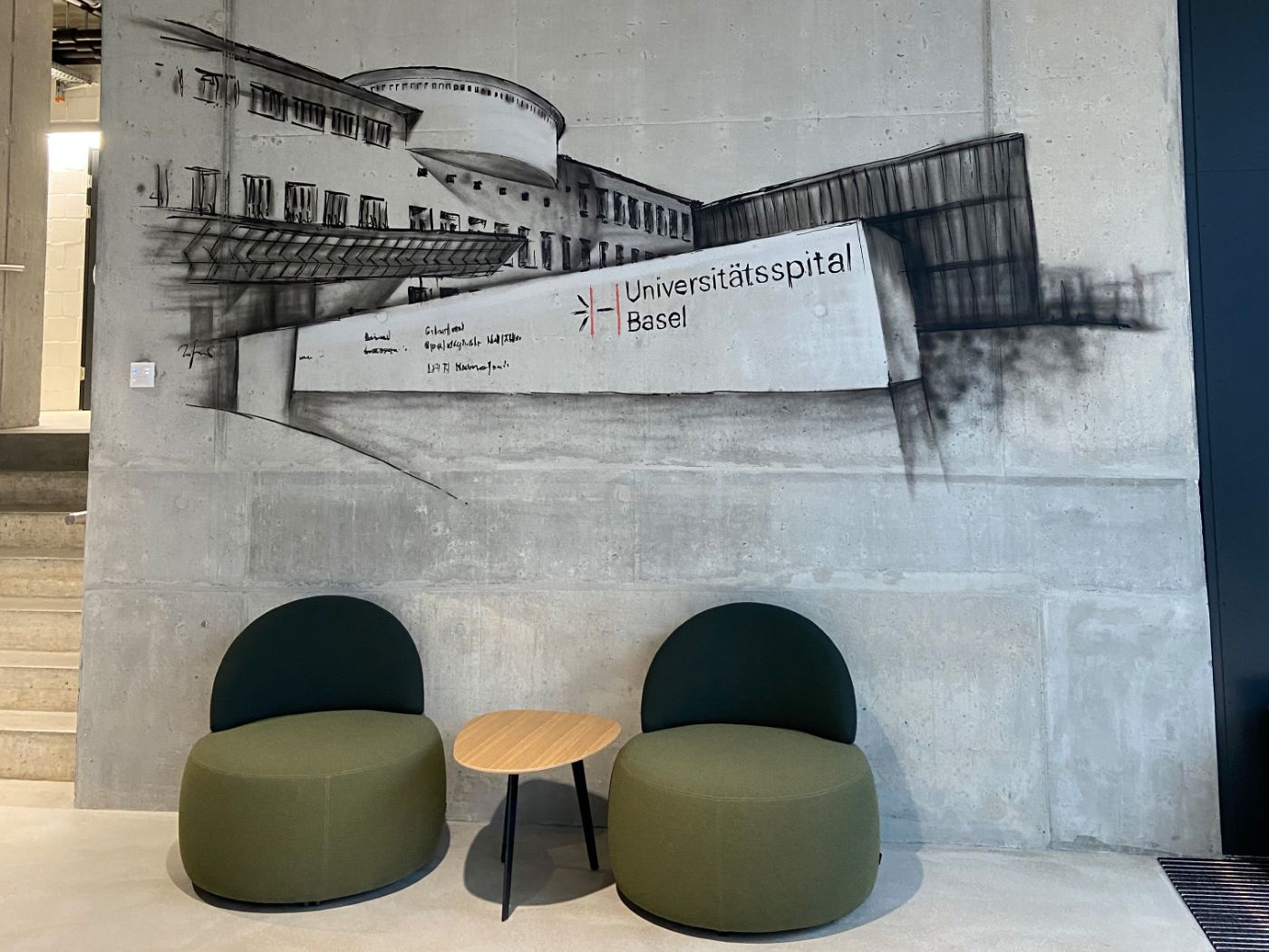 Im Eingangsbereich empfängt ein grossflächiges Wandbild vom Klinikum 1 in der aus der Spitalstrasse in Basel die Besucher.