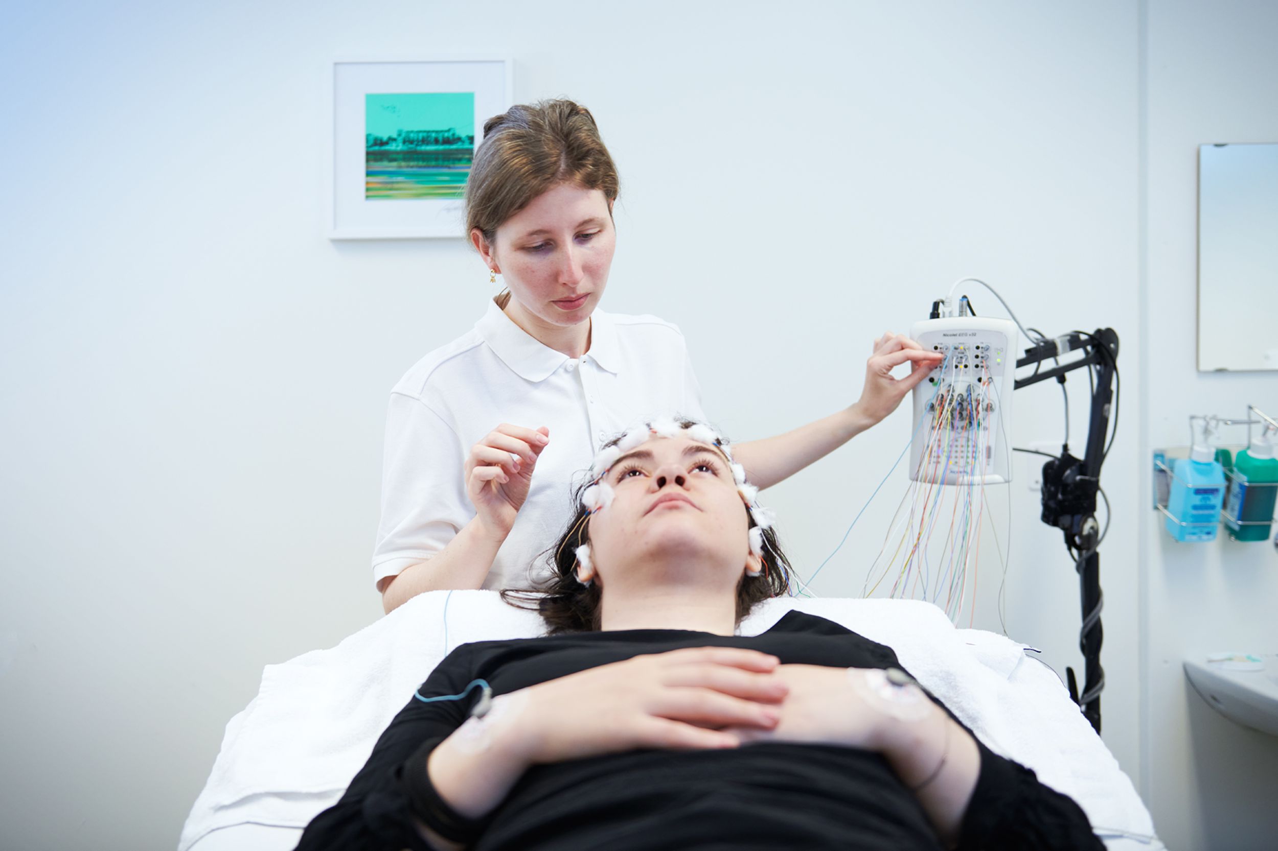 Mitarbeiterin der Neurologie bereitet eine EEG-Untersuchung (Hirnstromkurve) bei Patientin vor