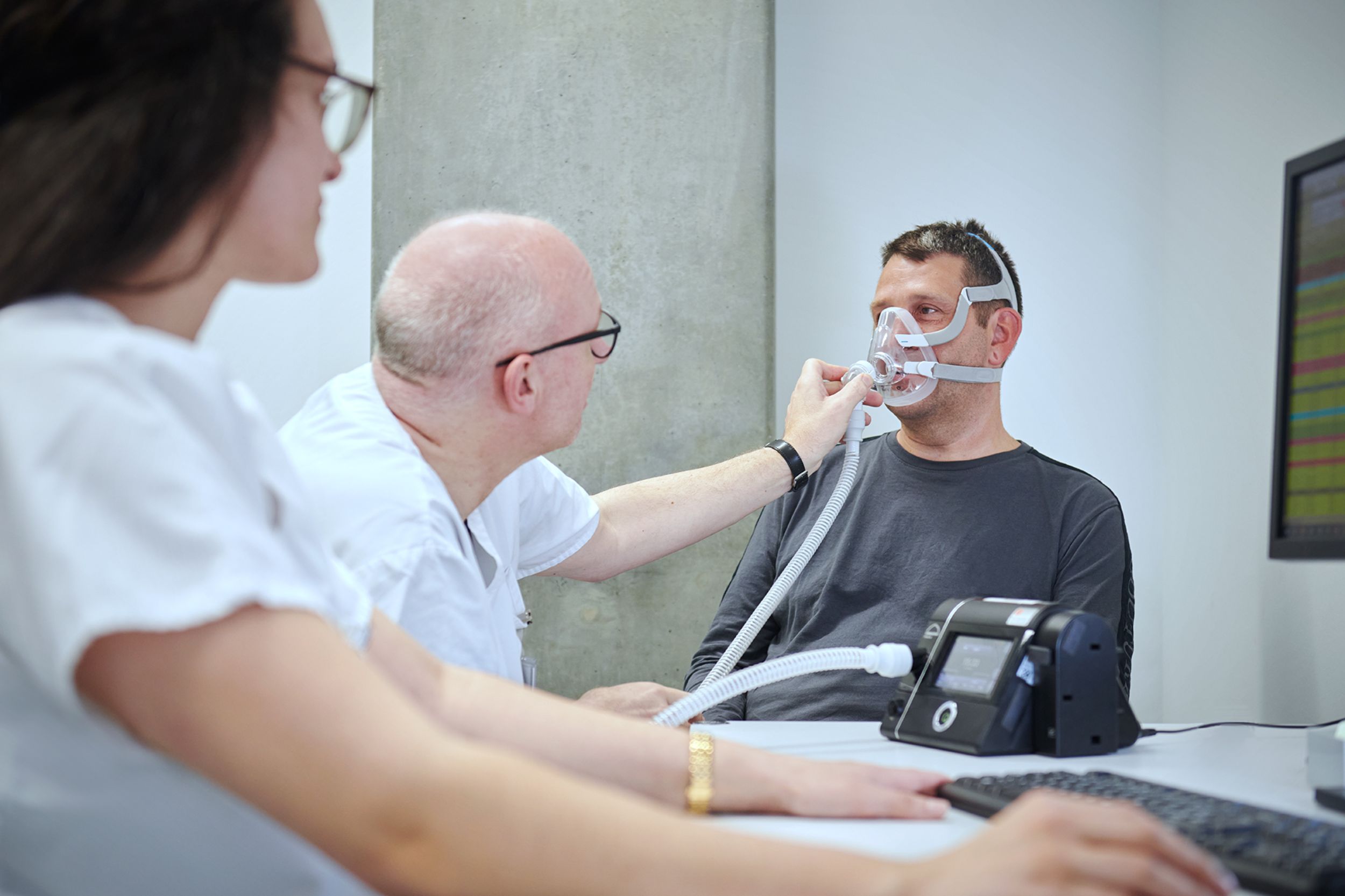 Arzt hilft Patient bei der Erstbenutzung einer Schlafmaske