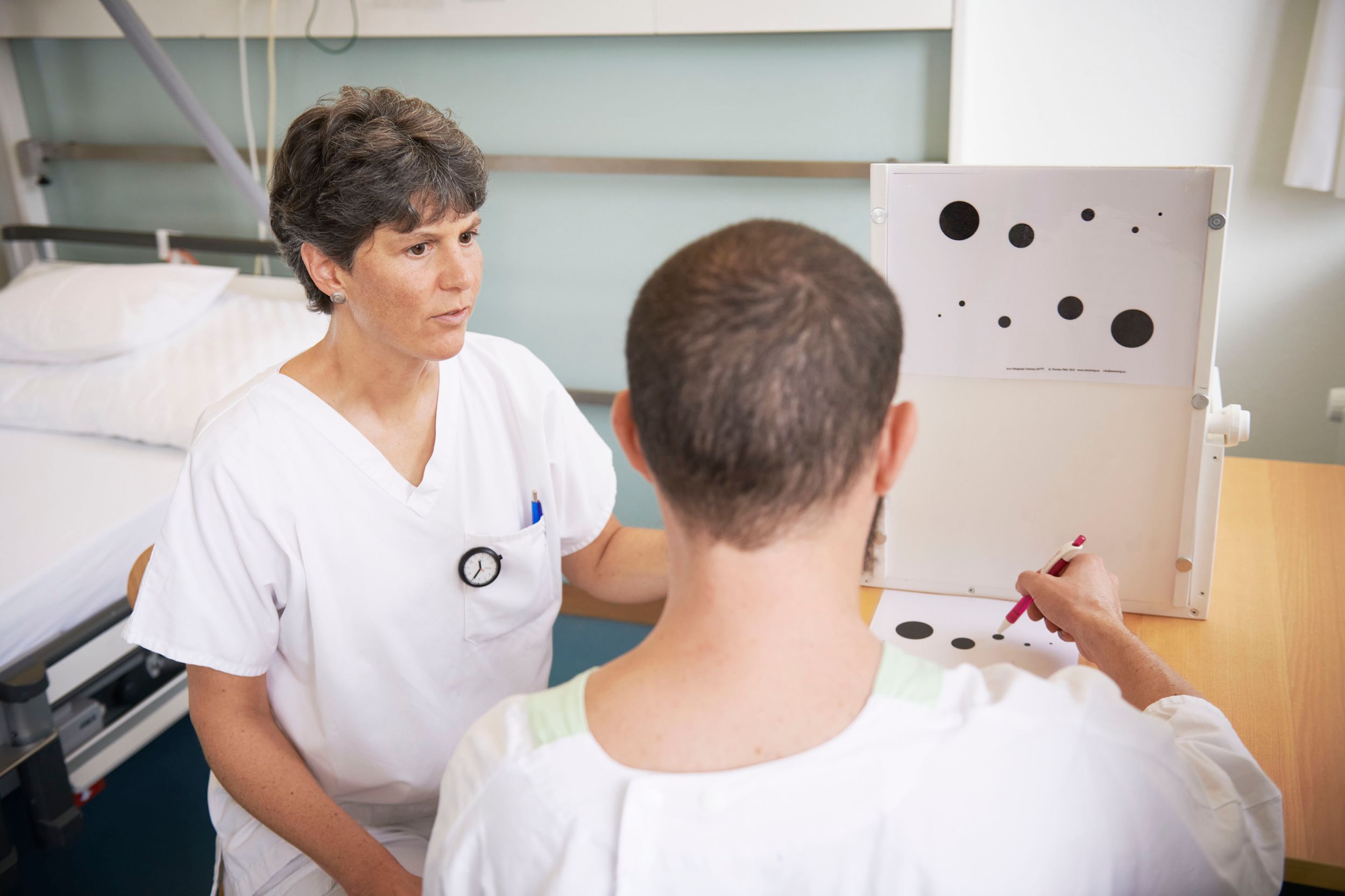 Ergotherapeutin führt mit Patient verschiedene Tests durch