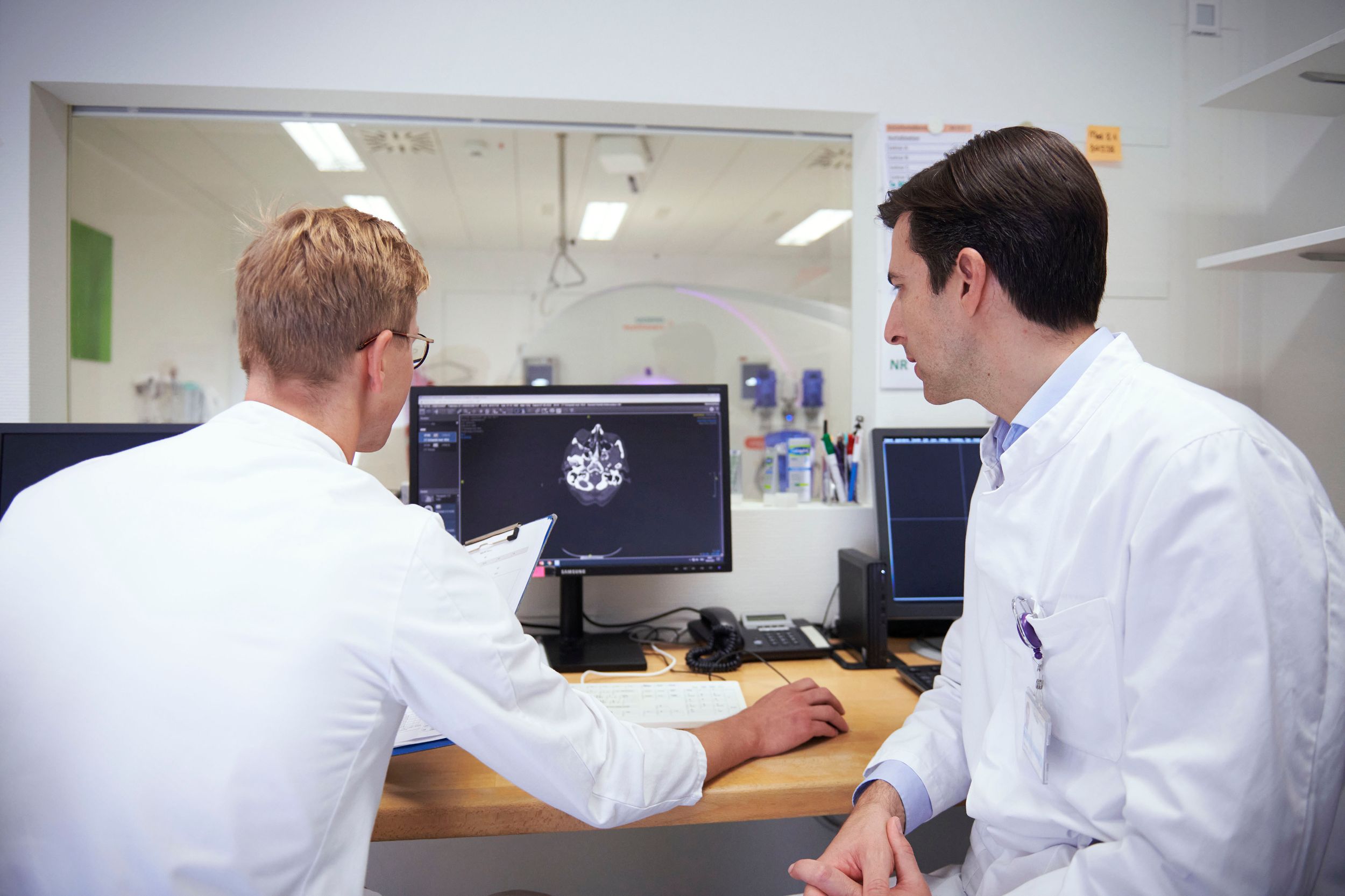Zwei Ärzte schauen auf einem Bildschirm die Röntgenaufnahmen von einem Hirn an 