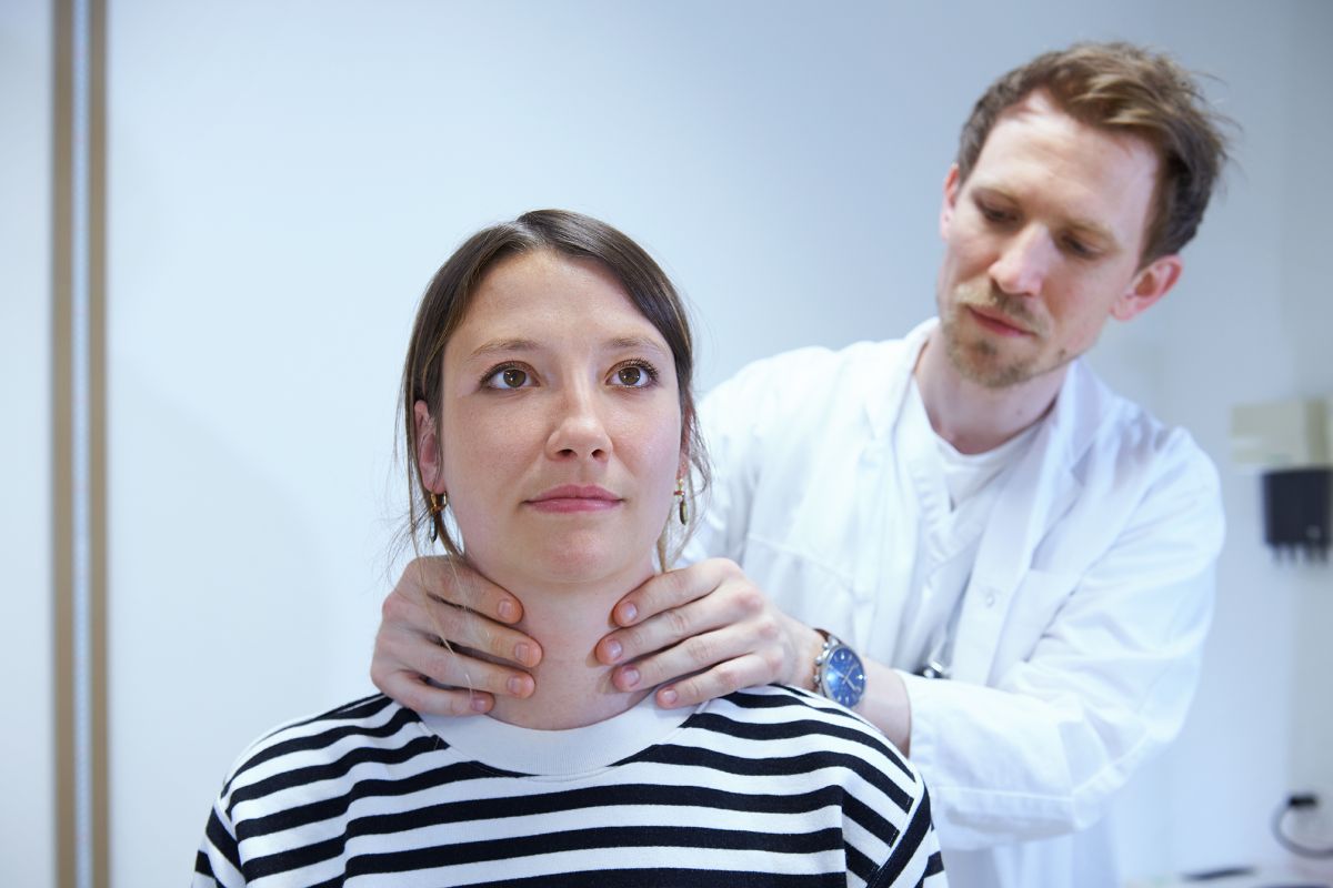 Arzt tastet Hals von Patientin ab