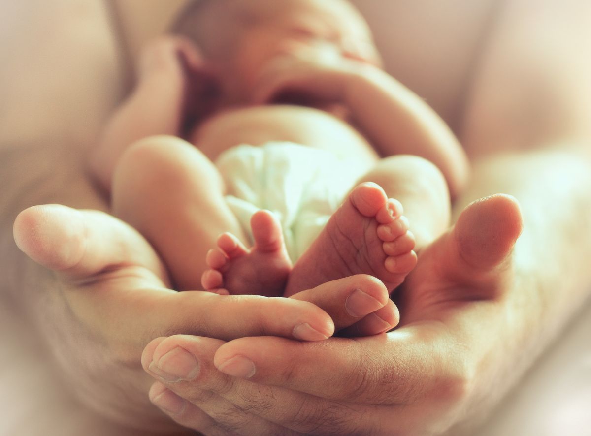 Ein Baby wird gehalten von zwei Händen