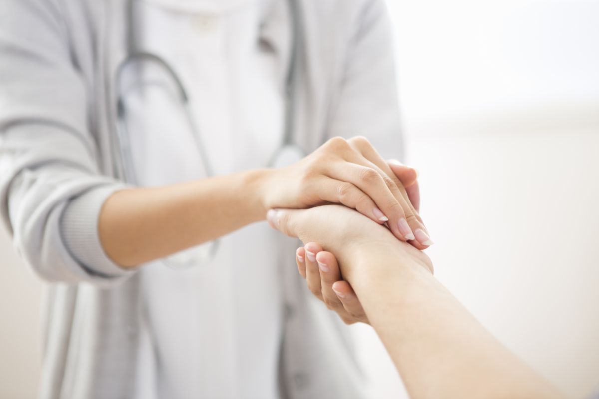 Ärztin hält Hand von Patientin