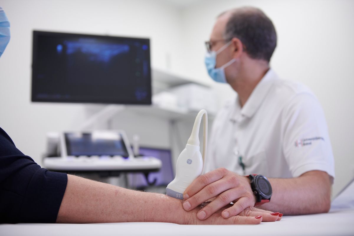 Arzt führt eine Ultraschall-Untersuchung an Hand von Patientin durch