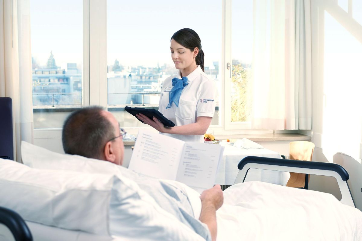 Ein Patient liegt im Bett und liest die Menükarte.
