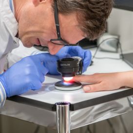 Prof. Alexander Navarini untersucht den Finger einer Patientin