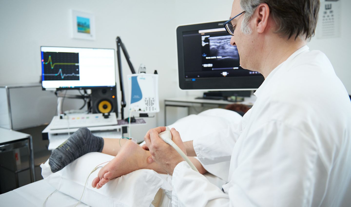 Arzt führt EMG-Untersuchung bei Patientin durch